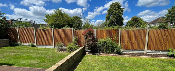 Garden view featuring a well-maintained lawn, wooden fencing, and a variety of plants under a bright blue sky with fluffy clouds. An ideal setting for outdoor living.